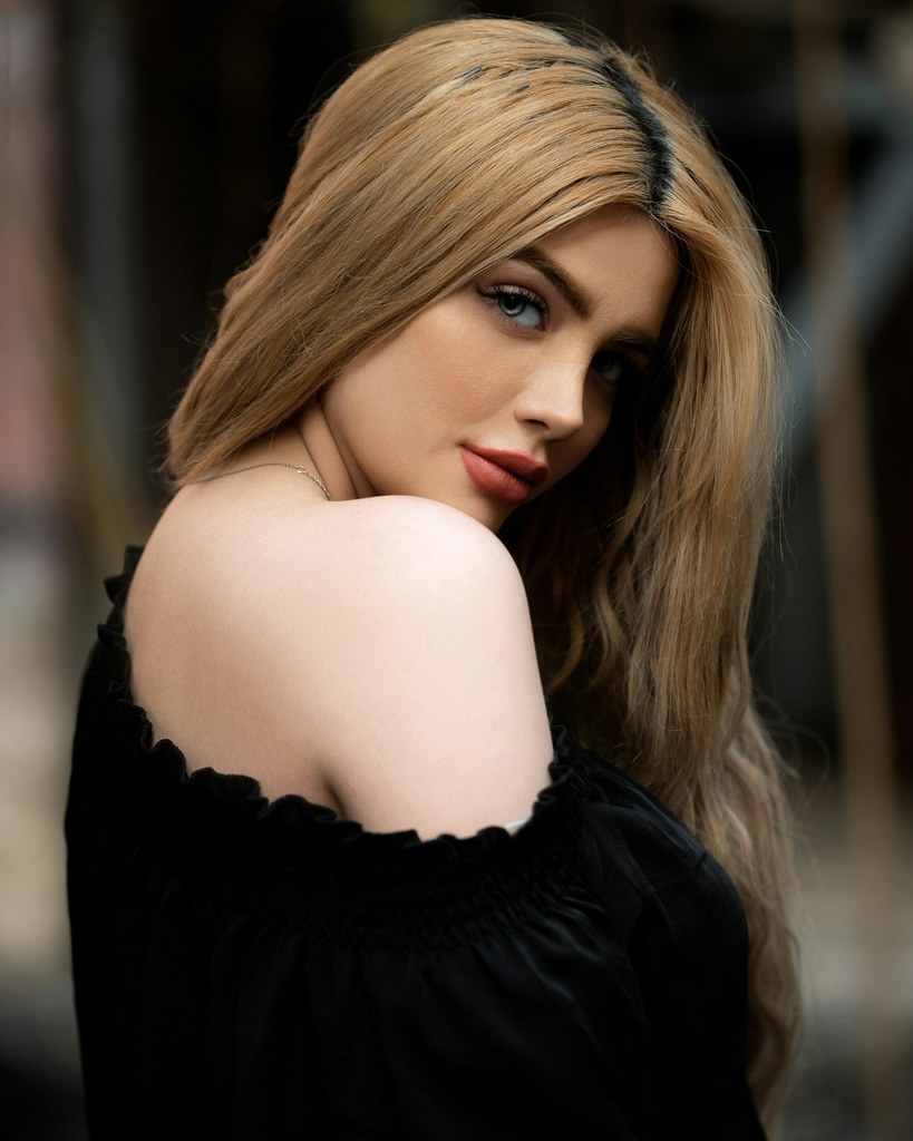 A stock photograph of a woman looking back over her bare shoulder, in soft daylight