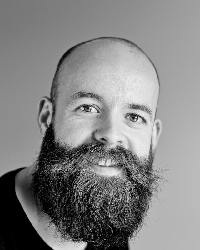 A black and white stock portrait of a bearded man